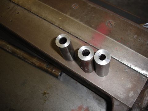 1996 Ford Bronco - Three machined metal parts are shown on a workbench surface.
