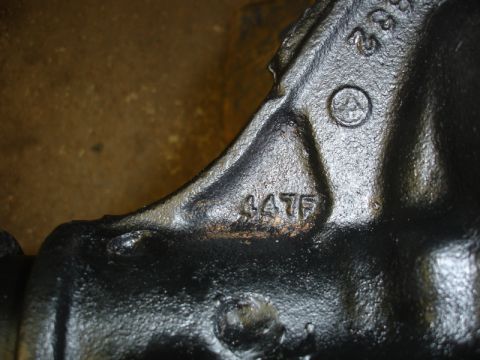 1996 Ford Bronco - Close-up of a black cast iron component showing stamped numbers and a circular emblem.