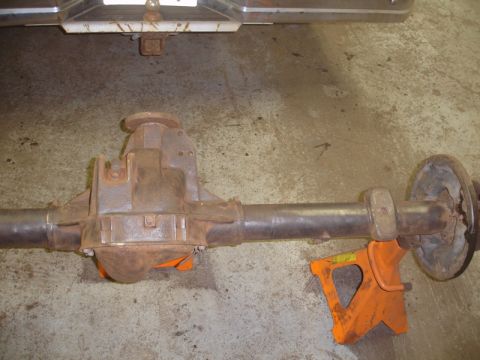 1996 Ford Bronco - A rusty rear axle assembly is supported by orange jack stands on a concrete floor.