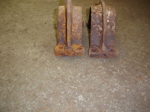 1996 Ford Bronco - Two heavily rusted metal brackets are shown on a concrete floor.