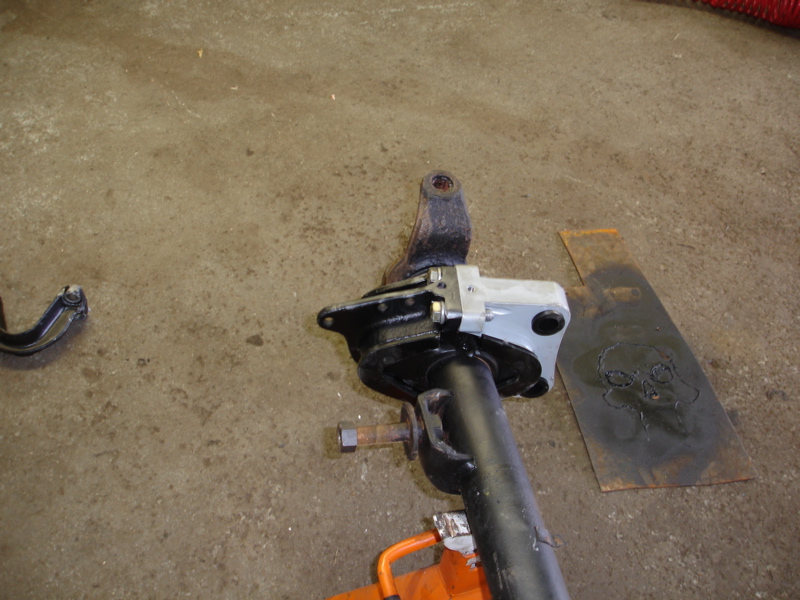 Black suspension strut assembly with silver bracket and rusty bolt on concrete floor
