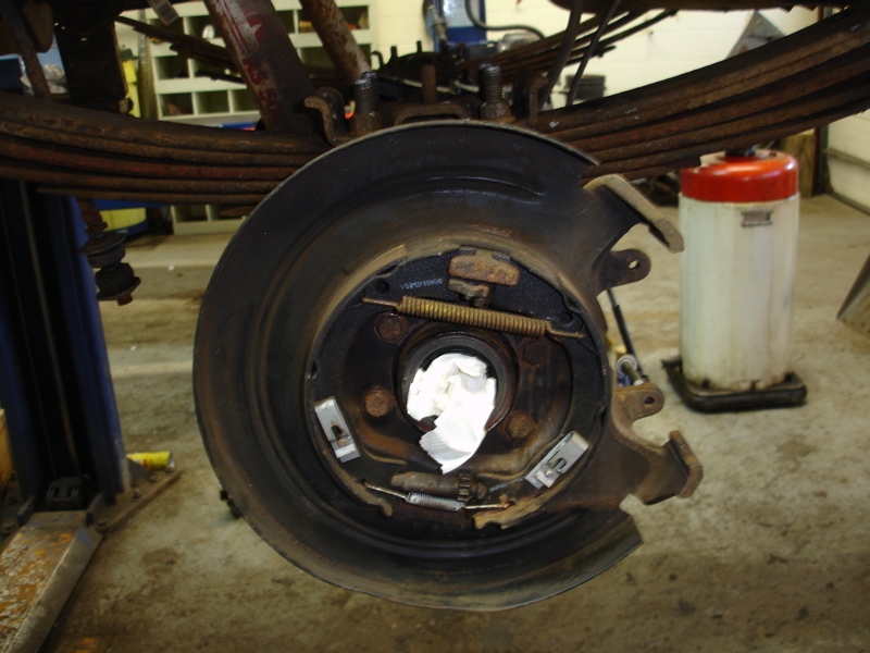 Rear brake assembly with drum removed, showing shoes, springs, and backing plate