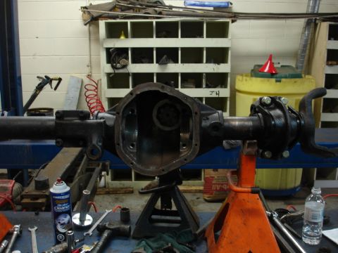 1996 Ford Bronco - A disassembled differential axle assembly is supported by jack stands in a workshop environment.