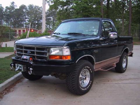 1995 Ford Bronco - This 1995 Ford Bronco features a dark green exterior, an aftermarket bumper, and a winch, seen from a 3/4 front angle.