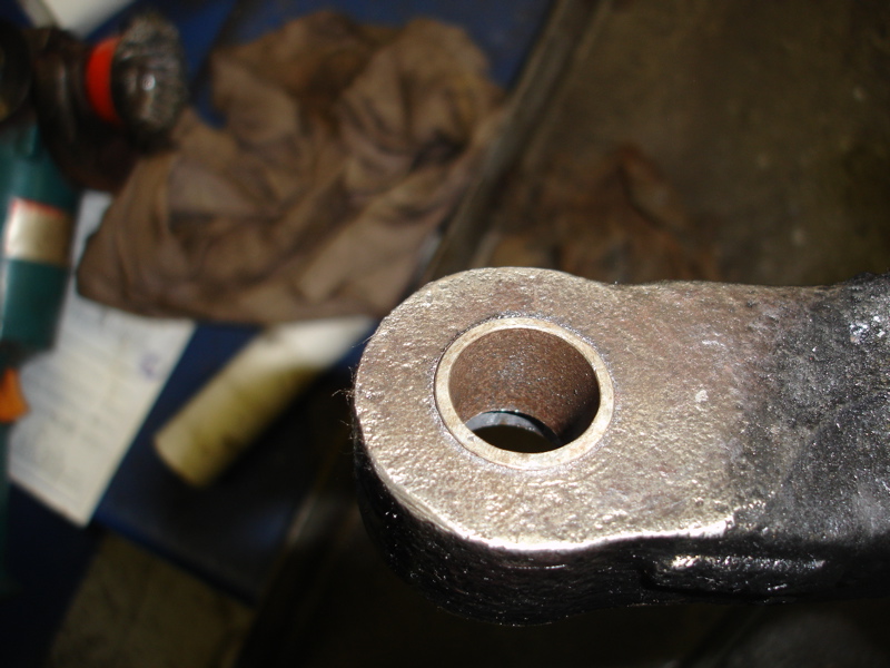 Close-up of a worn metal part with a central hole, showing rust and grease
