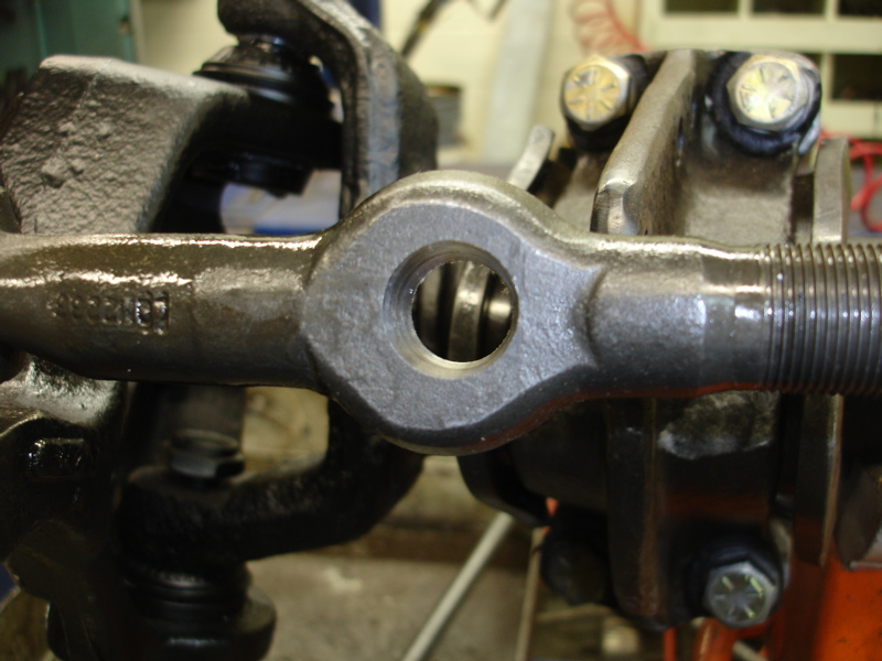 Close-up of a metal steering linkage component with a hole in the center