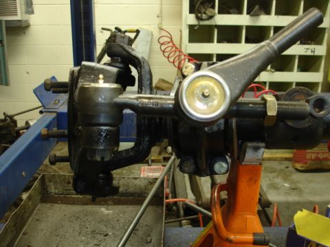 1996 Ford Bronco - Steering and suspension components are shown disassembled, supported by a jack stand in a workshop.