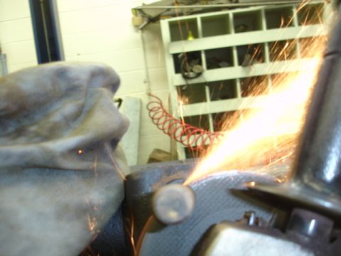 1996 Ford Bronco - A gloved hand operates a grinder, sending sparks flying as a metal part is worked on.