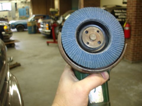 1996 Ford Bronco - Angle grinder with a blue flap disc is held in a hand, with a workshop in the background.