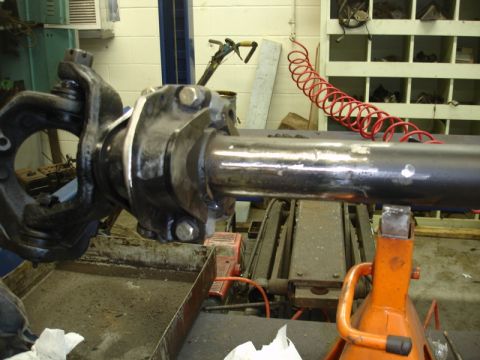 1996 Ford Bronco - A vehicle axle assembly is supported by an orange jack stand in a workshop environment.