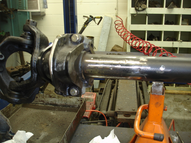 Close-up of a vehicle axle assembly on an orange jack stand in a workshop