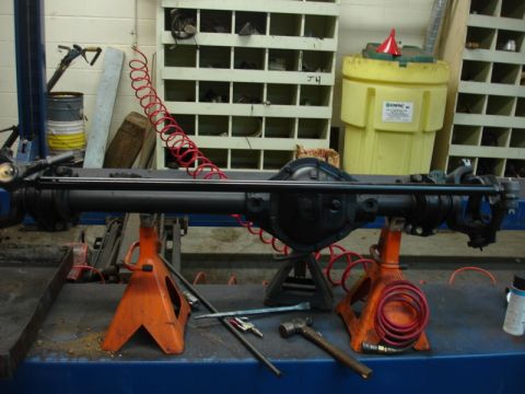 1996 Ford Bronco - Front axle assembly supported by jack stands in a workshop environment.