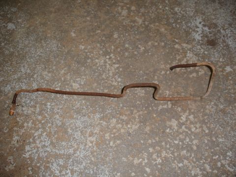 1996 Ford Bronco - A single, heavily rusted metal brake line lies on a concrete surface, indicating a need for replacement.