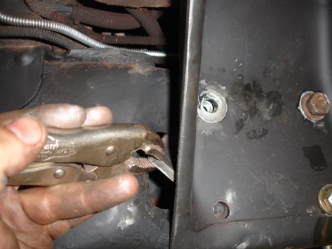 1996 Ford Bronco - Close-up of a hand using vice grips on a vehicle's metal frame, with visible wiring and a cable.