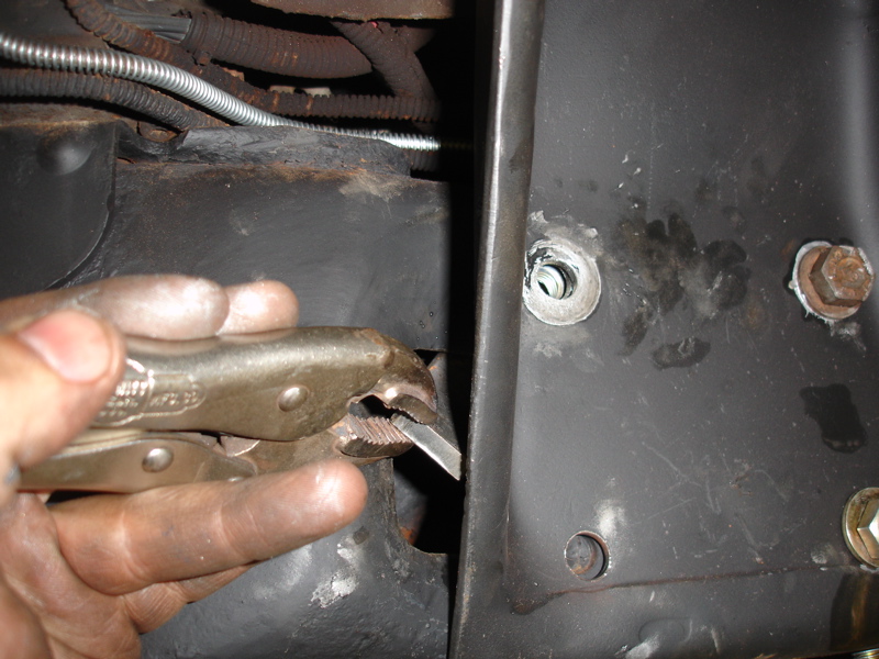 Hand holding vice grips to a metal frame with wires and a cable nearby