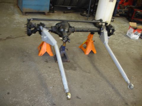 1996 Ford Bronco - A front axle assembly, likely for an off-road vehicle, is supported by jack stands in a workshop.
