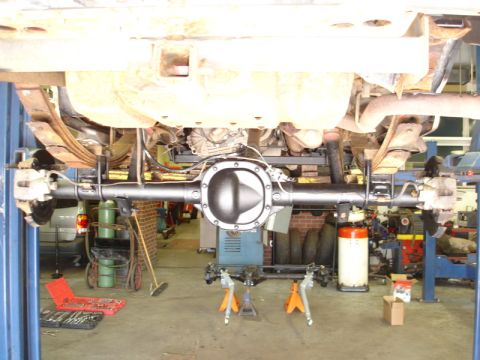1996 Ford Bronco - Vehicle's rear axle assembly is shown disassembled and supported by jack stands in a workshop.