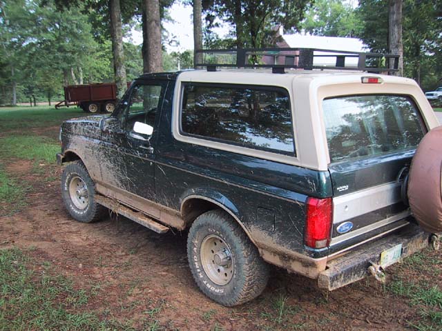 Mud-covered 1992 Ford Bronco with a roof rack and a spare tire on the back