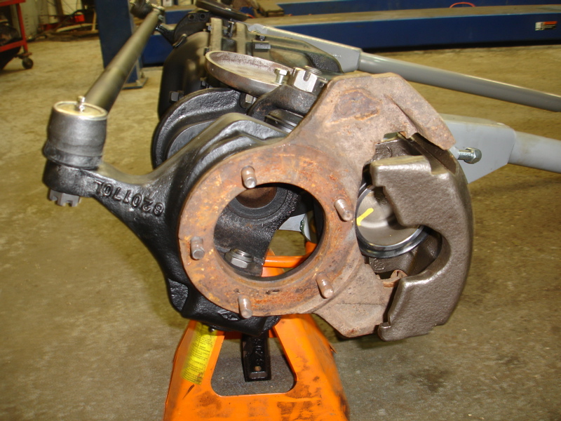 Close-up of a vehicle's front suspension knuckle with brake caliper and tie rod end. Part number 020770L is visible