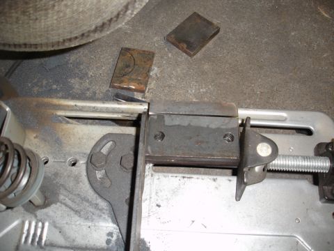 1996 Ford Bronco - A metal bracket is secured in a chop saw, ready for cutting, with two small metal plates on the ground nearby.