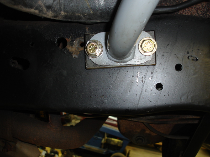 Close-up of a gray bar bolted to a black vehicle frame with rust spots