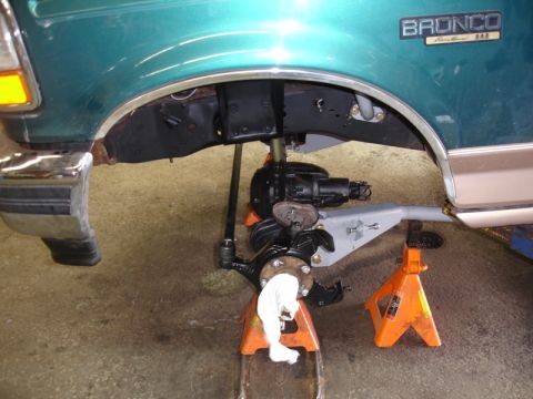 1996 Ford Bronco - The front suspension of a 1996 Ford Bronco is visible, supported by jack stands during maintenance.