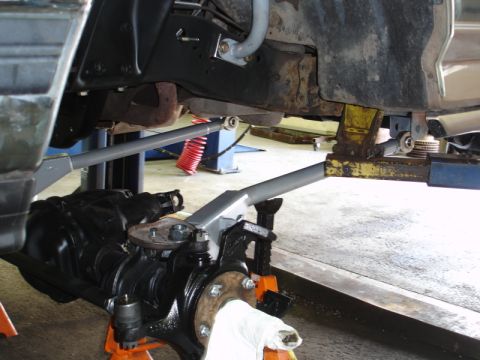 1996 Ford Bronco - Vehicle's front suspension and differential are visible while it's raised on jack stands for service.