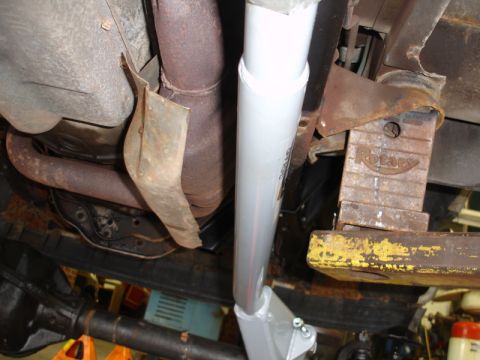 1996 Ford Bronco - The undercarriage of a vehicle is shown, supported by a jack, with visible exhaust components and drivetrain parts.