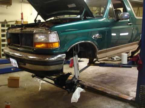 1996 Ford Bronco - A green 1996 Ford Bronco is undergoing service with its front end raised on a hydraulic lift.