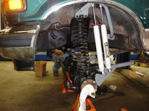 1996 Ford Bronco - The vehicle's front suspension system is undergoing maintenance and upgrades in a workshop setting.