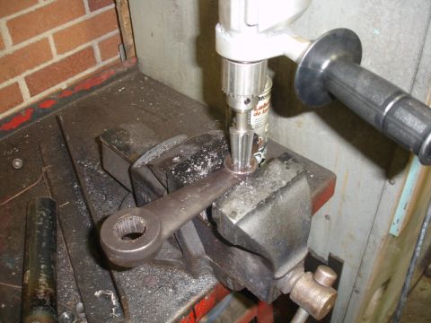 1996 Ford Bronco - A drill press is used to work on a metal component secured in a vise, with metal shavings scattered around.