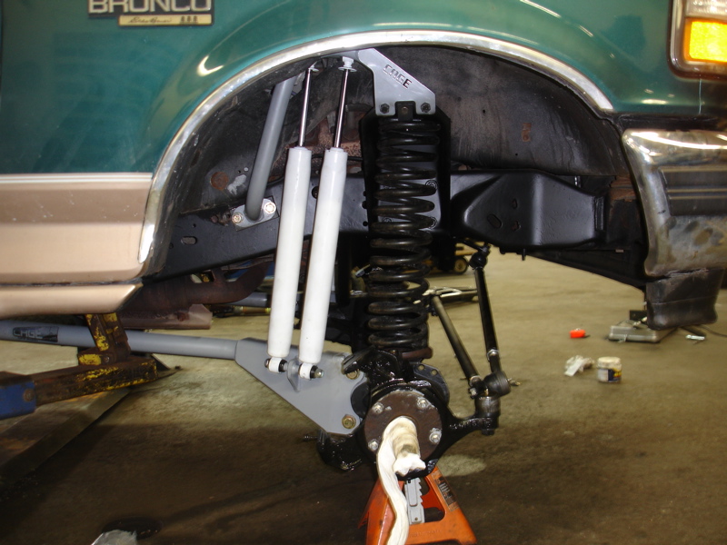 Green 1996 Ford Bronco front suspension with dual white shocks and black coilover