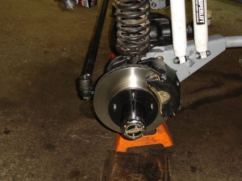1996 Ford Bronco - The vehicle's front suspension and braking system are shown, with the wheel removed and supported by jack stands.
