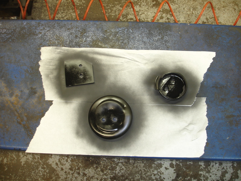 Three black painted metal parts on a white paper towel