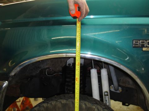 1996 Ford Bronco - A tape measure is used to check the clearance between the fender and tire on a 1996 Ford Bronco.