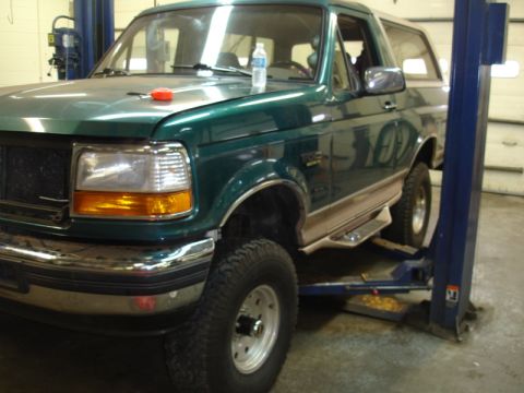 1996 Ford Bronco - A green 1996 Ford Bronco is positioned on a vehicle lift in a garage.