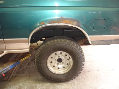 1996 Ford Bronco - The rear wheel well of a green Ford Bronco shows signs of rust and is fitted with an off-road tire.