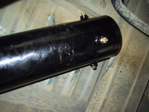 1995 Ford Bronco - Underside view of a black cylindrical tank with brass fittings, likely an air tank, mounted to a vehicle's chassis.