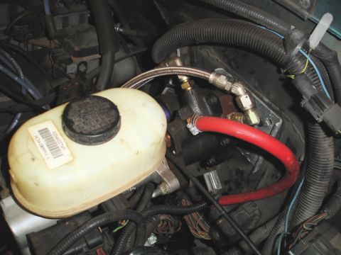 1996 Ford Bronco - Close-up of brake master cylinder and fluid reservoir with custom plumbing and red hose.