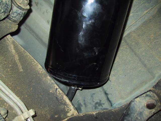 Close-up of a black cylindrical fuel filter attached to a vehicle's undercarriage