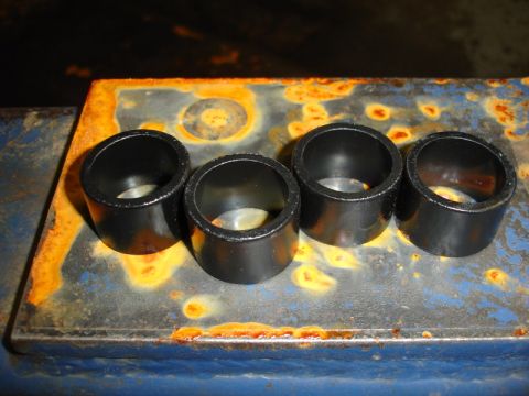 1996 Ford Bronco - Four black bushings are arranged on a rusty metal plate.