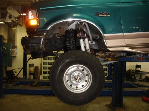 1996 Ford Bronco - A green 1996 Ford Bronco is shown on a lift, highlighting its modified suspension and off-road tire.