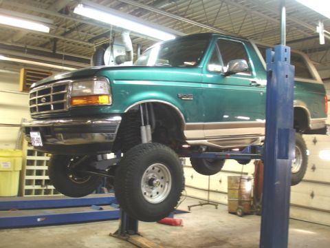 1996 Ford Bronco - 1996 Ford Bronco undergoing service on a lift in a workshop.