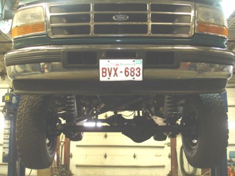 1996 Ford Bronco - Front view of a green Ford truck on a lift, revealing its grille, headlights, and suspension system.