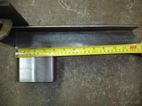 1996 Ford Bronco - A metal bracket is measured with a tape measure, indicating its dimensions.