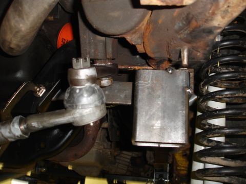 1996 Ford Bronco - Underside view of a vehicle's steering and suspension system, showing various metal components and a coil spring.