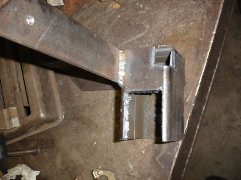 1996 Ford Bronco - A close-up view of a metal bracket that has been welded together, resting on a workbench.