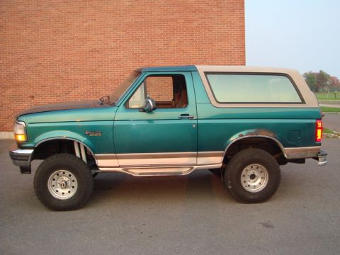 1996 Ford Bronco - Side view of a green 1996 Ford Bronco with a tan removable top and aftermarket wheels.