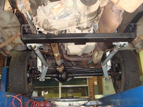 1996 Ford Bronco - A view from underneath a vehicle shows the transfer case and suspension system components.
