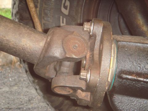 1996 Ford Bronco - Close-up view of a rusty driveshaft universal joint connected to a vehicle's differential.